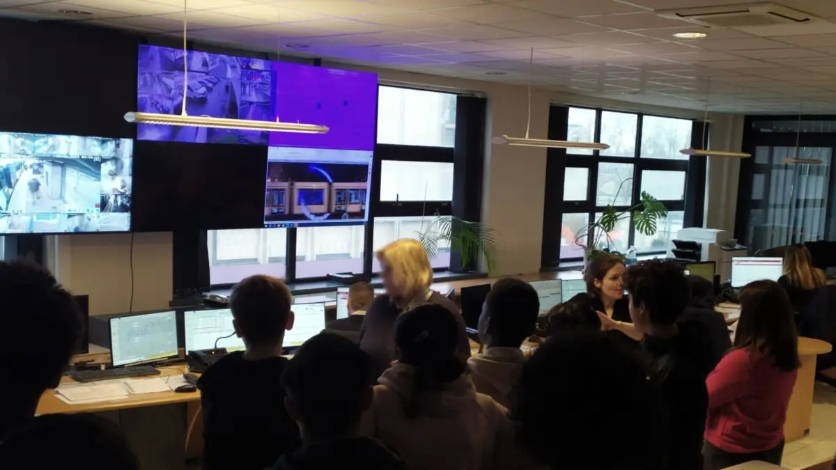 L'interprète traduit en langue des signes la présentation d'un poste de supervision, devant un groupe de visiteurs.